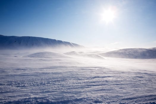 A winter landscape with a mountain and blue sky