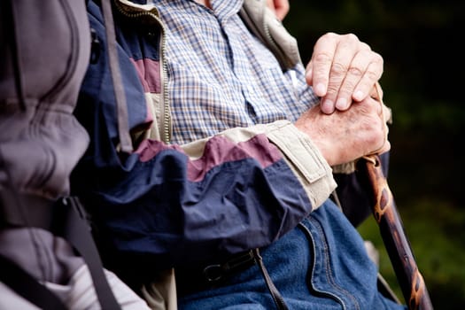 A detail of an elderly man outdoors with a walking stick