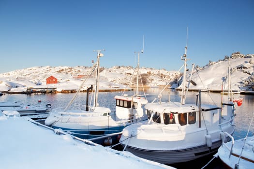 A dock in southern Norway with boats covered in snow