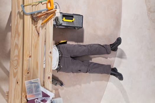 Man working under the wooden plank with tools