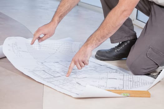 Close-up of man pointing finger at blueprint