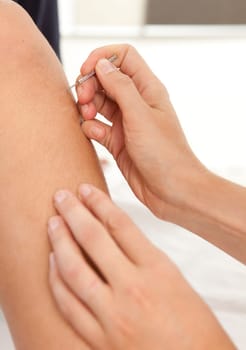 Shonishin Japanese pediatric acupuncture brush being used on leg of young male patient.
