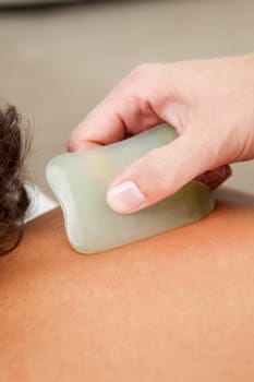 Detail of back fo young male receiving gua sha acupuncture treatment