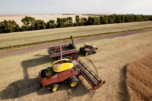 Large combine unloading seed into a grain cart on a prairie field