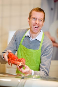 A man at a grocery store selling a lobster