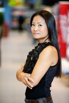 Asian woman standing in a supermarket looking at the camera