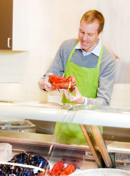 A fresh fish counter in a grocery store - clerk with a lobster