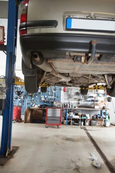 Car under repair on service lift in garage