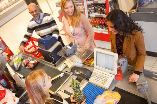 High angle view of cashier with a line of people at the check-out counter