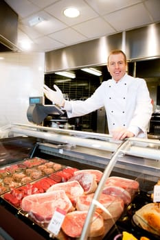 Portrait of a happy butcher welcoming customers to the shop