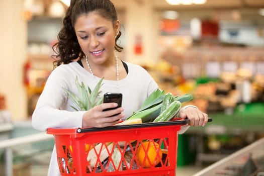 Smiling young woman using mobile phone while shopping in shopping store