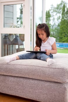A young child playing with a digital tablet in a living room interior