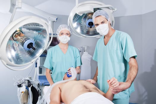 Female doctor applying gas and male doctor checking pulse rate of patient