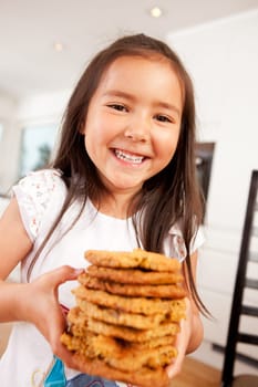 Happy, laughing and smiling young cute girl holding stack of large home made cookies