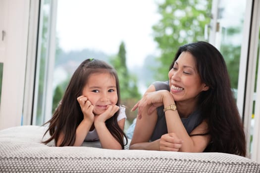 Portrait of mother and daughter lying on couch