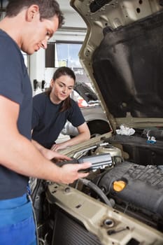 Two mechanic workers with diagnostics tool