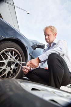 Business man changing a tire on the street