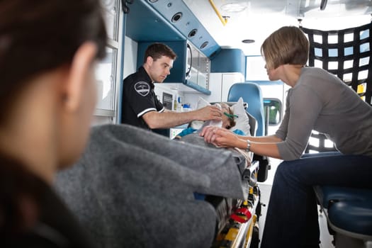 Senior woman being given oxygen in an ambulance, caregiver at side