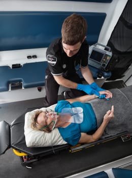 Male ambulance worker taking pulse of elderly senior woman