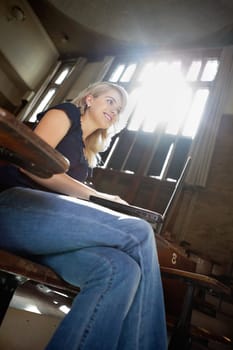 Low angle view of young college girl using laptop at seminar hall