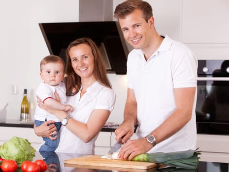 Portrait of a happy family at home in the kitchen preparing a meal