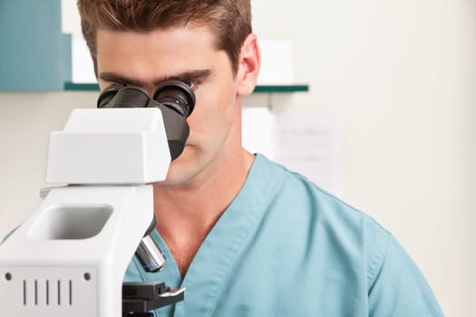 Closeup of young male doctor viewing through microscope