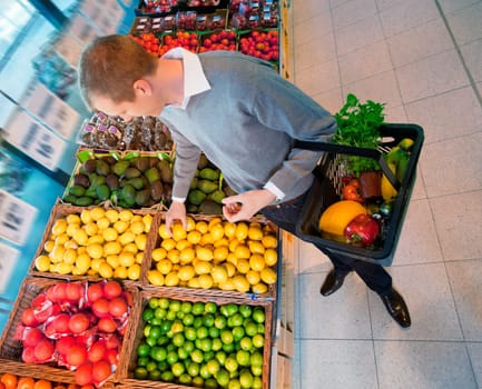 High angle view of a man carrying basket while buying fruits in the supermarket