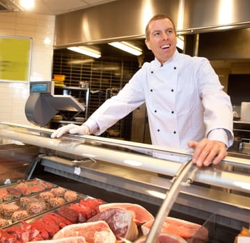 View of frozen meat with cheerful chef in the background