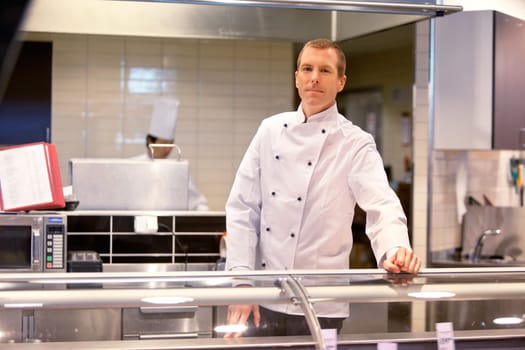 A butcher standing at a fresh meat counter in a grocery store