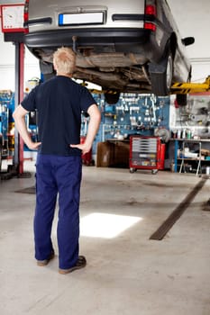 A young mechanic looking at a car that needs repair