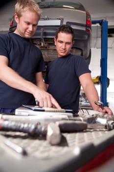 Two mechanics looking at work order and discussing repairs
