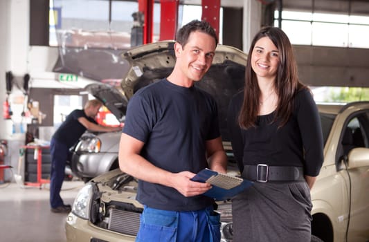 Portrait of a man mechanic with a woman customer going over the auto repair service report