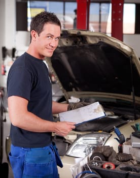 Portrait of a mechanic, looking at the camera with a service report in hand