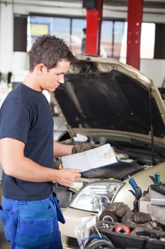 Three-quarter length of mechanic holding a work order