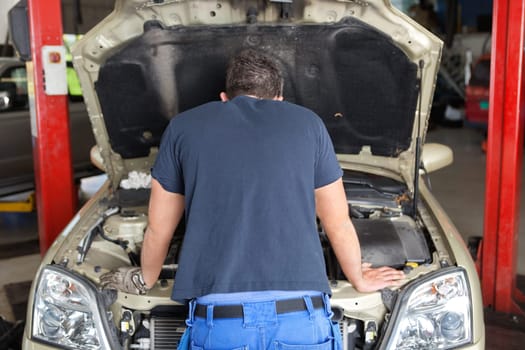 Rear view of mechanic working on a car in garage