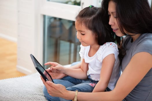 Mother and daughter reading electronic book at home