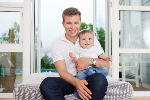 Portrait of smiling young father with child sitting on couch