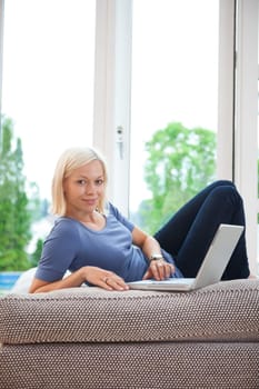 Portrait of pretty female using laptop while sitting on couch