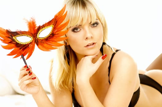 Portrait of attractive beautiful young woman on bed with red mask