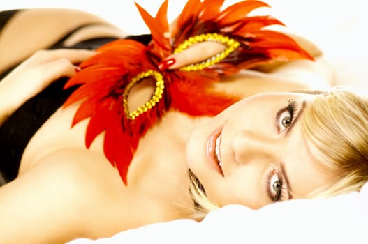 Portrait of attractive beautiful young woman on bed with red mask