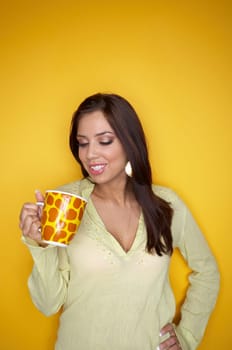 Portrait of Young woman isolated on yellow background with cup