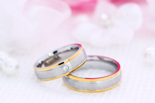 Wedding still life with beautiful golden rings and bouquet in background