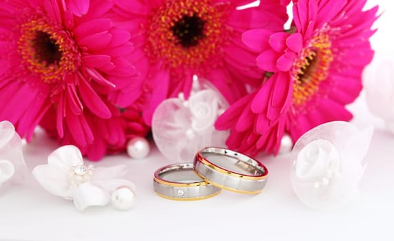 Wedding still life with beautiful golden rings and bouquet in background
