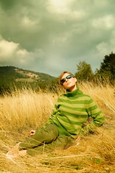 Young business woman relaxing on golden meadow at mountains outdoors