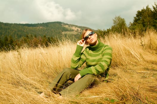 Young business woman relaxing on golden meadow at mountains outdoors