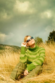 Young business woman relaxing on golden meadow at mountains outdoors