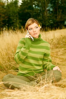 Young business woman using cell phone on golden meadow at mountains outdoors