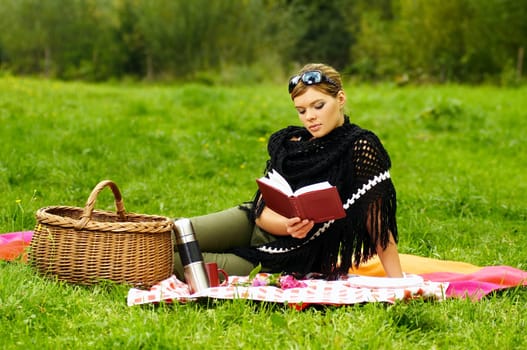 Young business woman with book during picnic on green meadows outdoors
