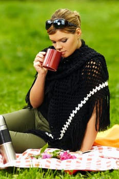Young business woman with cup during picnic on green meadows outdoors