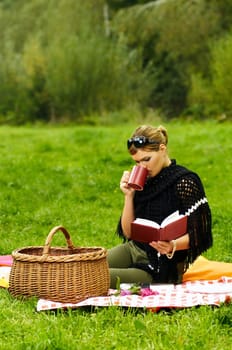 Young business woman with cup during picnic on green meadows outdoors